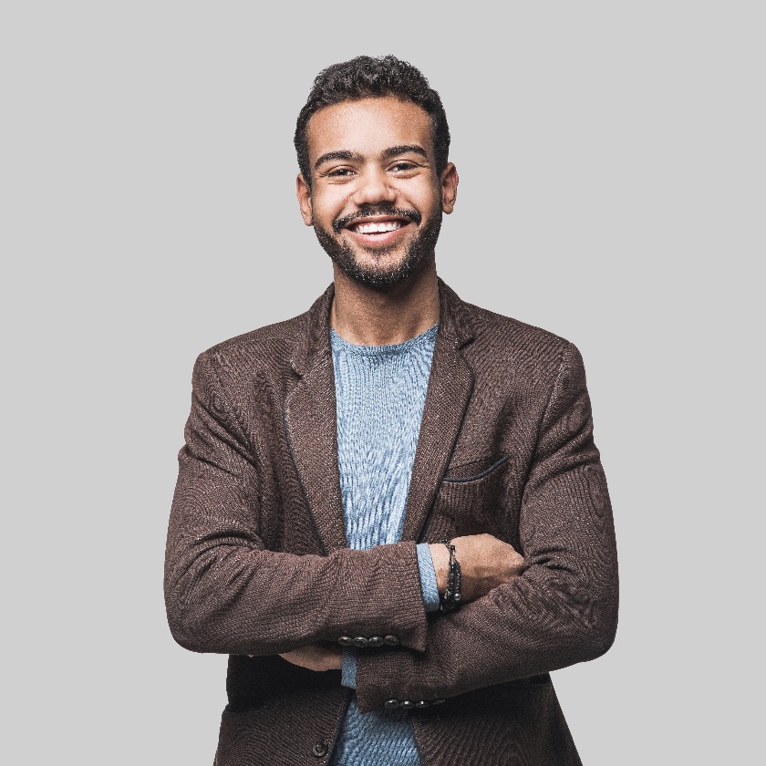 Porträt eines gut aussehenden, lächelnden jungen Mannes mit verschränkten Armen. Lächelnd