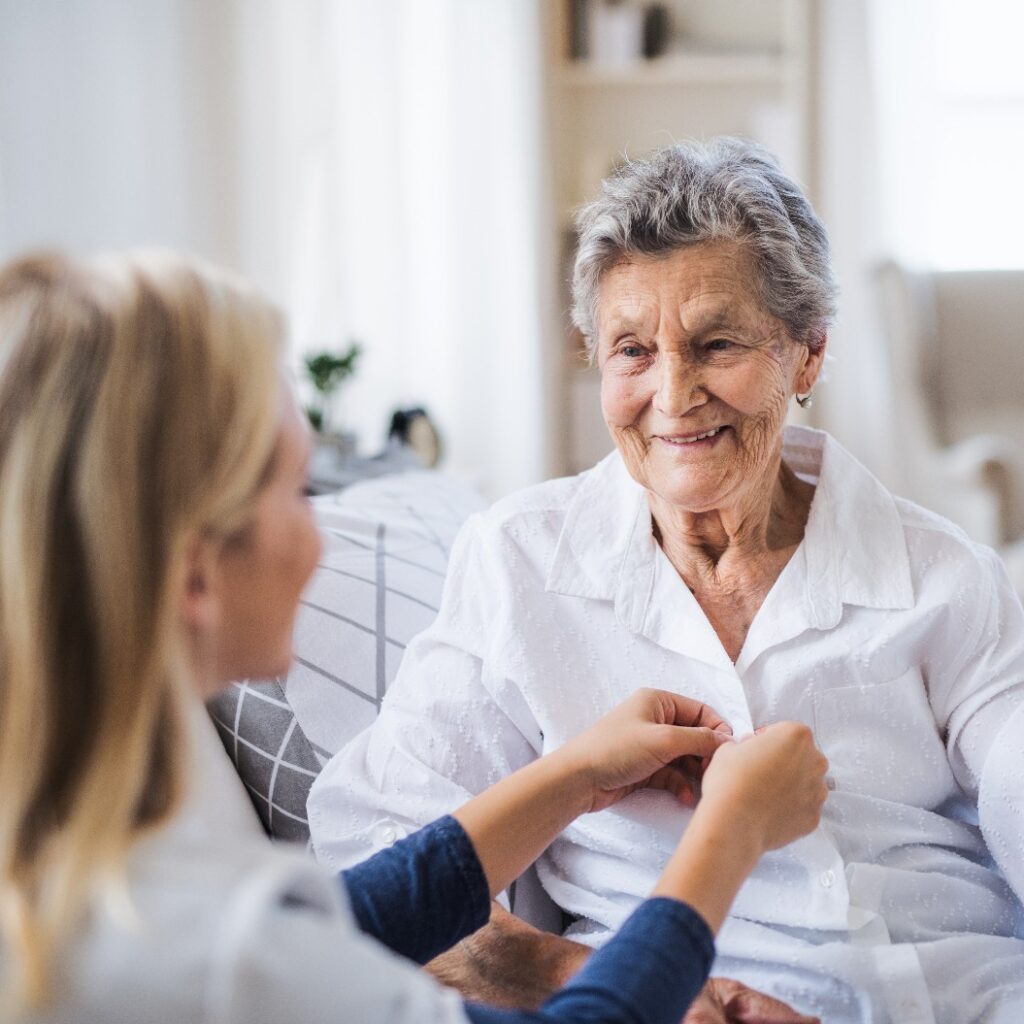Eine Gesundheitsberaterin hilft einer kranken älteren Frau, die zu Hause im Bett sitzt.