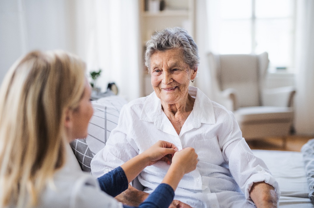 Eine Gesundheitsberaterin hilft einer kranken älteren Frau, die zu Hause im Bett sitzt.
